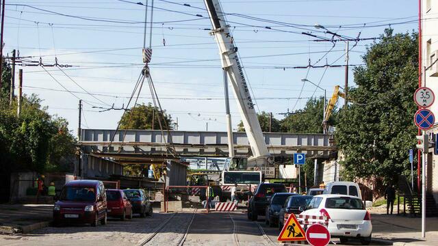 На улице Суворова пешеходы ходят под железнодорожным мостом во время его демонтажа
