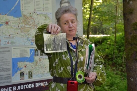 Елена Васильевна Ермоленко показывает школьникам фотографию из личного архива, где изображены Геннадий Юшкевич, Наполеон Ридевский и Иван Целиков на открытии памятника командиру разведгруппы «Джек» Павлу Крылатых