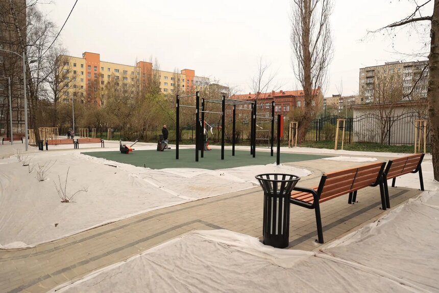 Спортивная площадка с безопасным резиновым покрытием и тренажерами. Газоны пока накрыты специальной тканью от птиц. | Фото автора